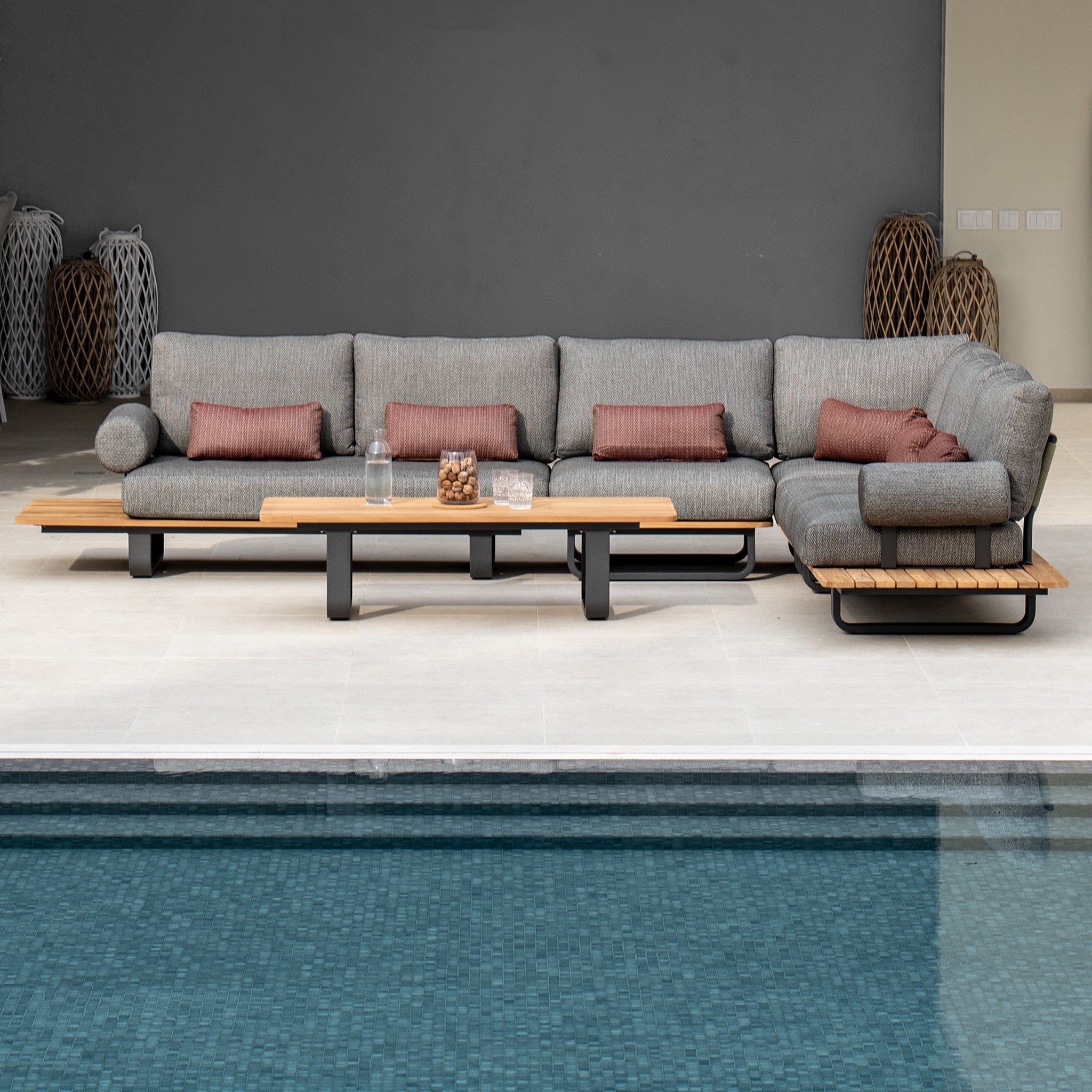 Modern outdoor seating area with a Bay Large Corner Group Set featuring an olive green sectional and a teak table beside a turquoise pool.