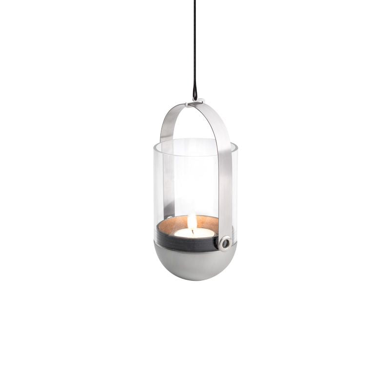 The Höfats GRAVITY CANDLE Hanger features a contemporary lantern design with a lit candle inside clear glass and a brushed solid stainless steel frame, all suspended by a black cord.