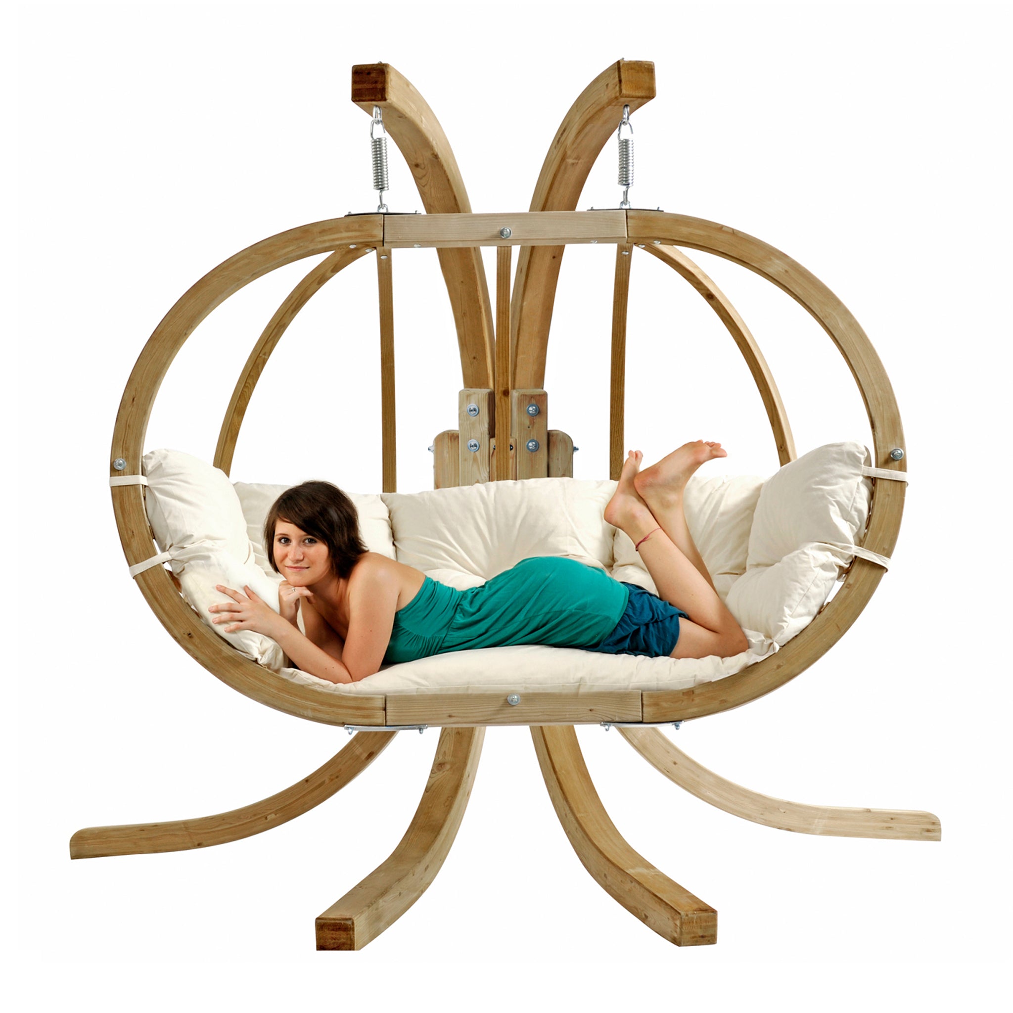 A woman in a green dress lies on a cushioned, Globo Royal Double Seater Hanging Chair in Natura crafted from weatherproof spruce wood, with a unique organic shape perfect for outdoor use.