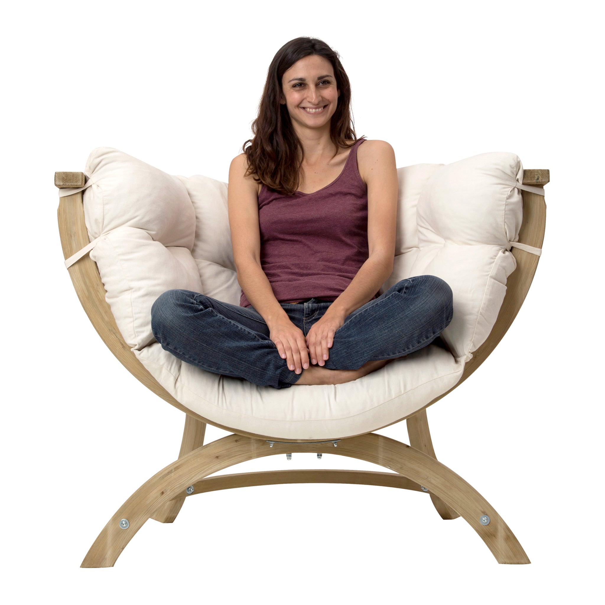 A woman sits cross-legged in a Globo Siena Uno Seat in Cream Beige, smiling and wearing a maroon tank top and jeans, enjoying the round, cushioned chair frame made of sustainably sourced wood.