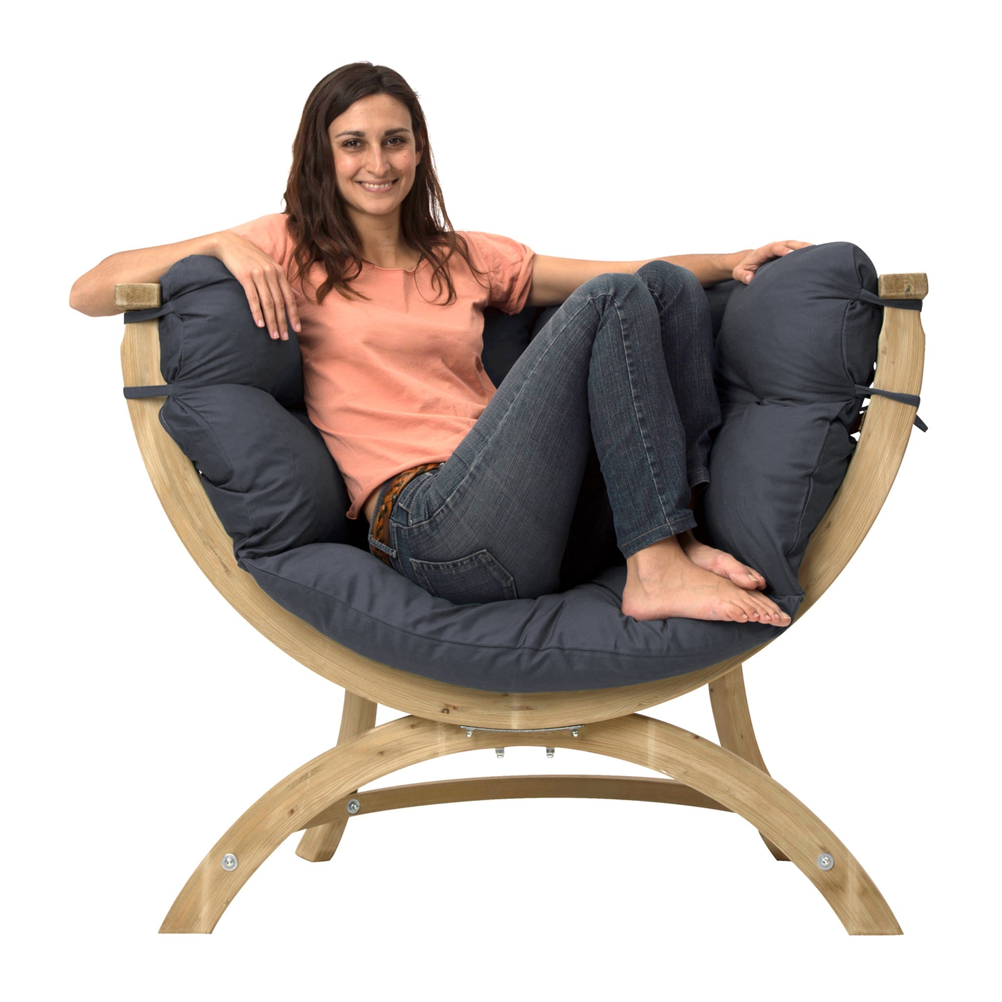 A smiling woman in a peach shirt and jeans sits comfortably on a cushioned wooden Globo Siena Uno Seat Weatherproof in Anthracite Grey, made from sustainably sourced wood.