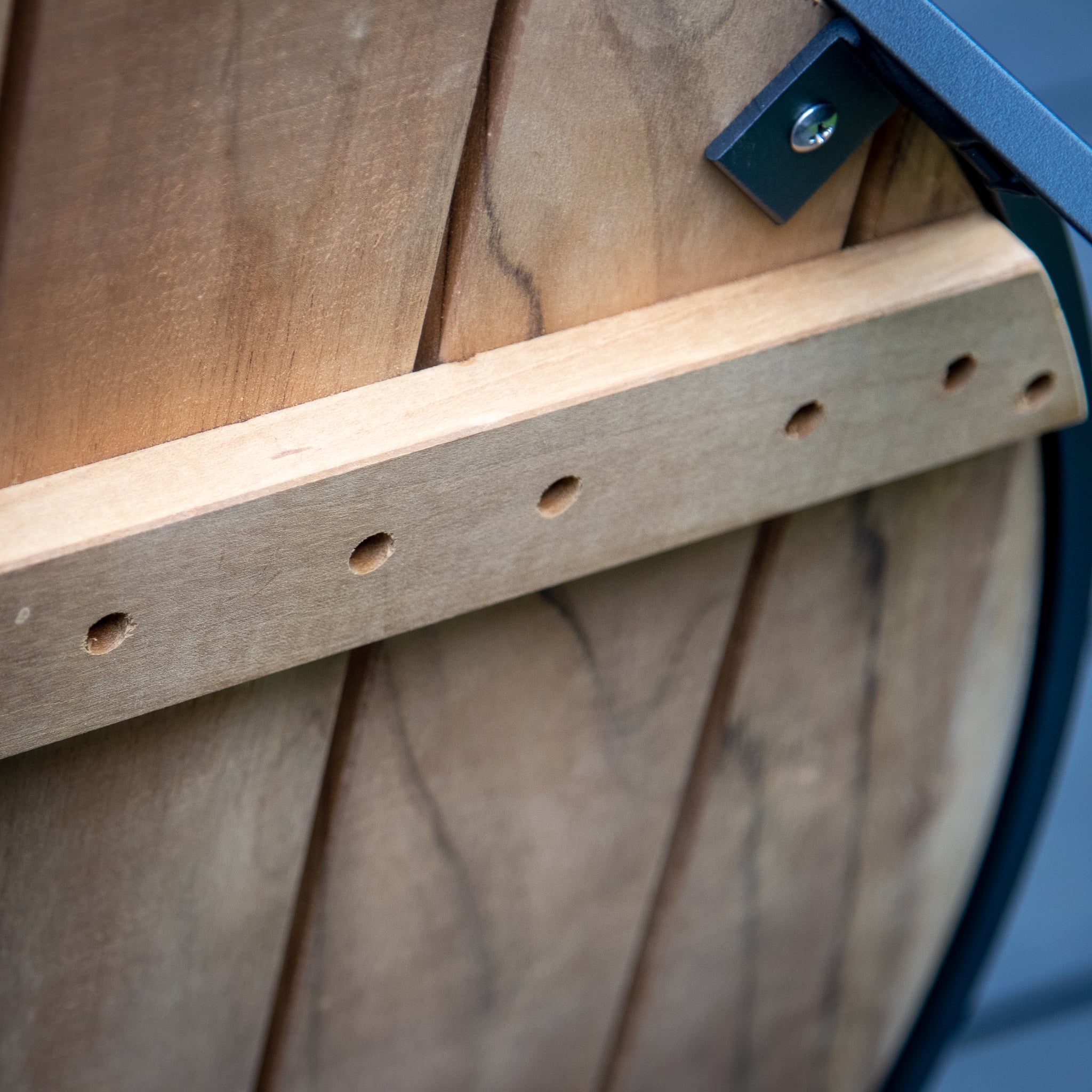 Close-up of wooden boards with a horizontal wooden brace and metal brackets, showcasing an outdoor furniture piece that could be the sturdy base of a Bloom Coffee Table with Teak Top in Charcoal.