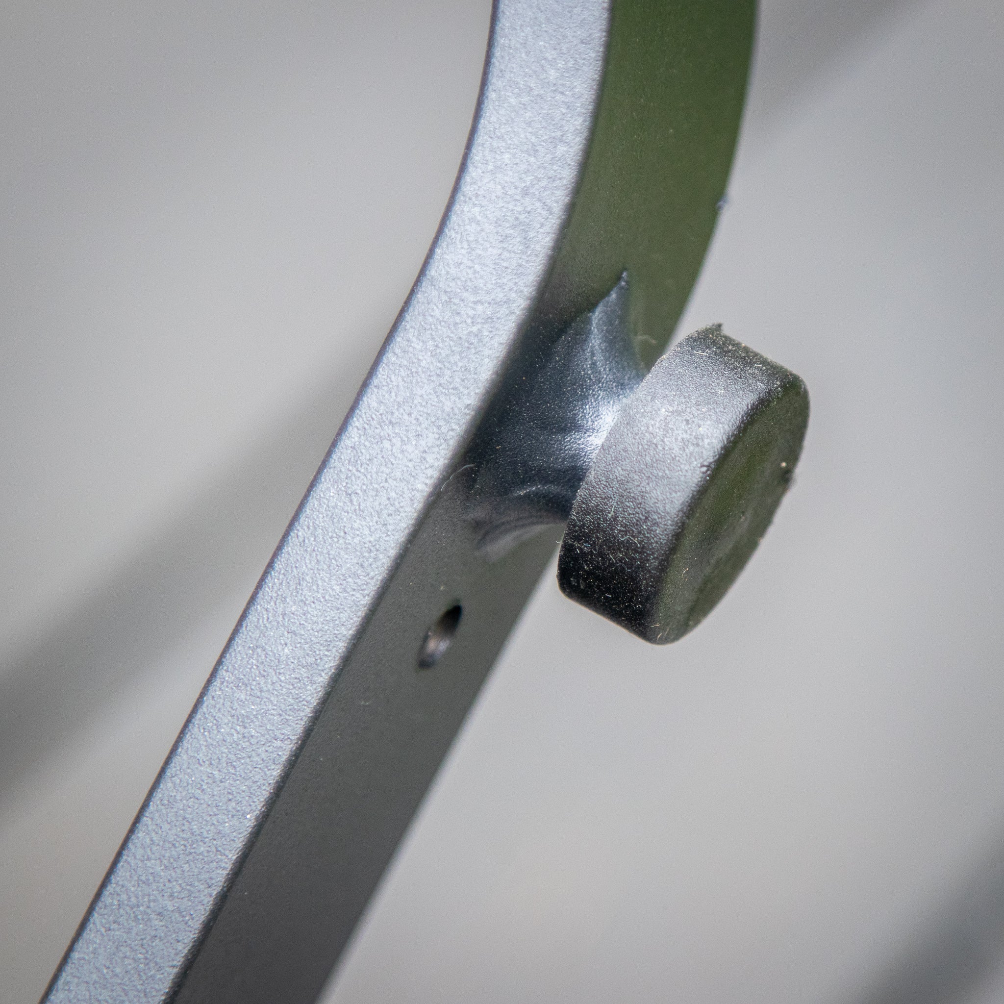Close-up of a metallic hinge joint with a bolt fastened in place, showing a textured surface and a small hole—perfect for securing the structure of the Bloom Coffee Table with Teak Top in Charcoal.
