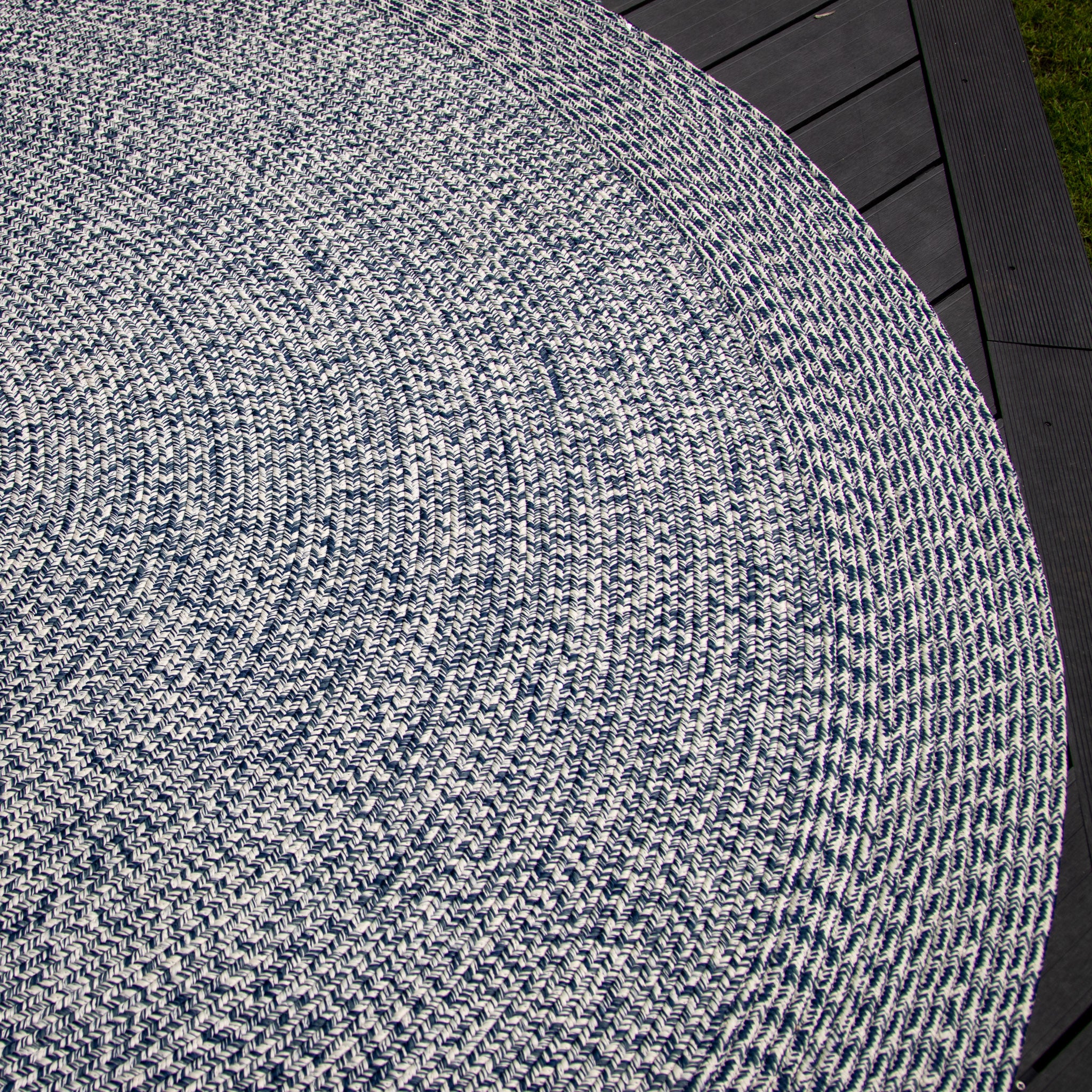 Close-up of the Apollo 300cm Round Indoor and Outdoor Rug in Prussian Blue, showcasing its round, woven design with a blue and white pattern, placed on a dark wooden deck. This UV-resistant and weatherproof accessory adds charm and durability to any space.