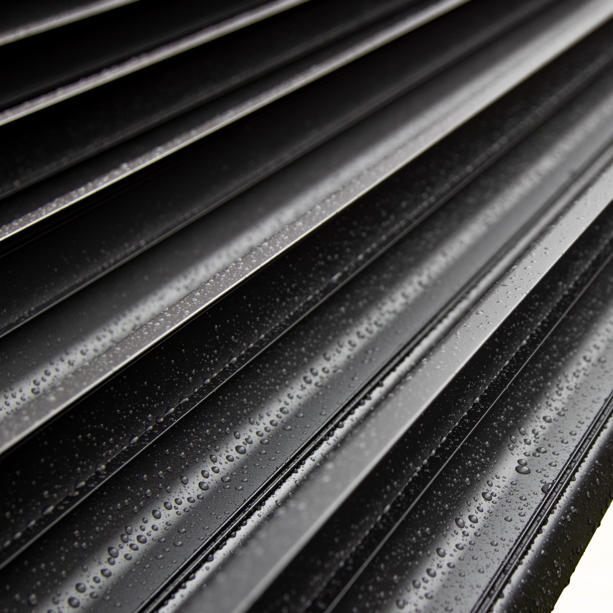 Close-up of water droplets on the sleek, grey surfaces of the PergoSTET Plus 4m x 4m Square Pergola, featuring shimmering LED lighting and a geometric pattern, perfect for outdoor living with its 3 drop sides.