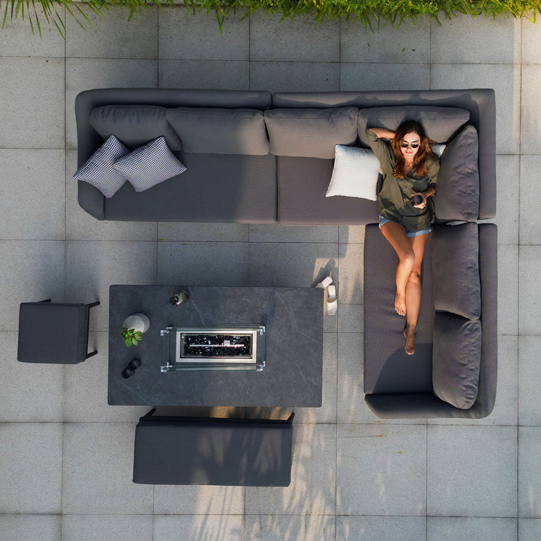 A woman relaxes on the Luna Outdoor Fabric Rectangular Corner Dining Set with Rising Firepit Table in Grey (Right Hand), viewed from above.