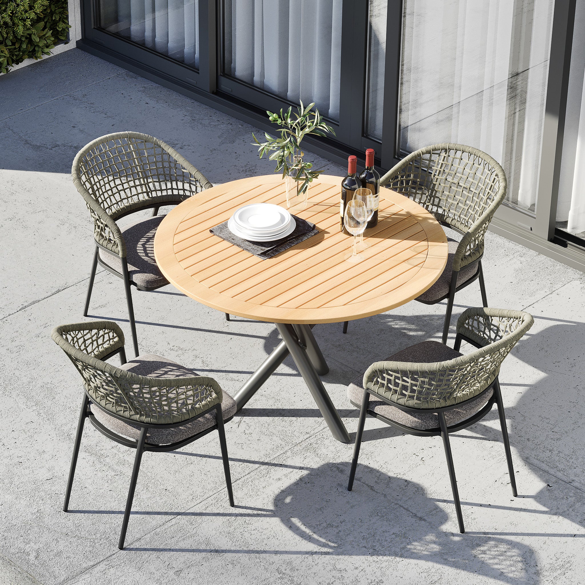 Kalama 4 Seat Round Dining Set with Teak Table in Olive Green, featuring a teak wood dining table, four woven chairs with sun-proof cushions, white plates, and glasses of wine on top.