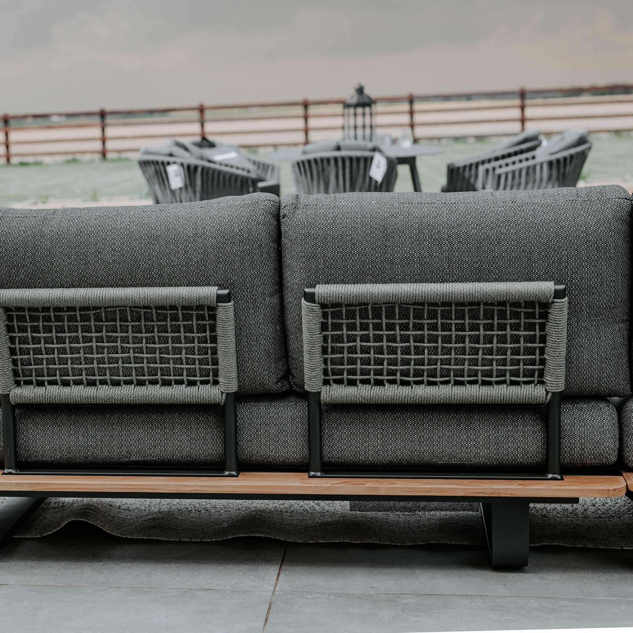 Outdoor seating arrangement featuring a Bay Corner Group Set with 4 waist pillows and a teak table in Olive Green, overlooking a patio with additional seating.