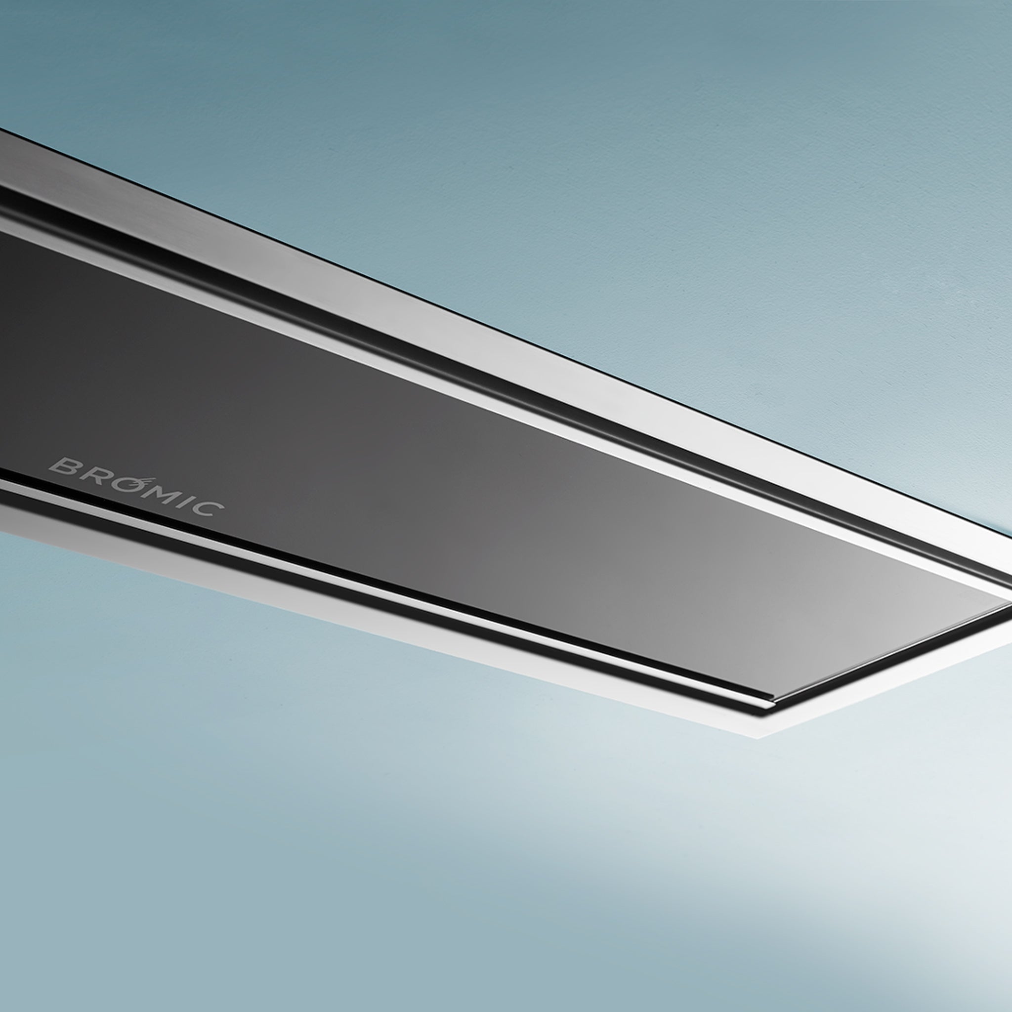 A sleek, modern, black and silver rectangular Bromic Platinum Electric Recess Kit For 2300W device is mounted on a light blue wall.