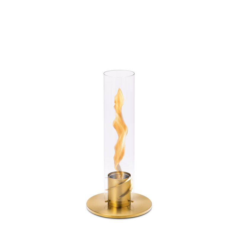 A cylindrical glass candle holder with a gold base, housing a vibrant Höfats SPIN 90 Table Top Fire in Gold inside.