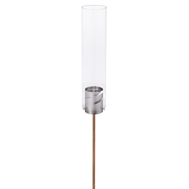 A modern outdoor torch, the Höfats SPIN Ground Spike Oak 3 part, features a sleek cylindrical glass cover and a metallic base on an adjustable wooden pole.