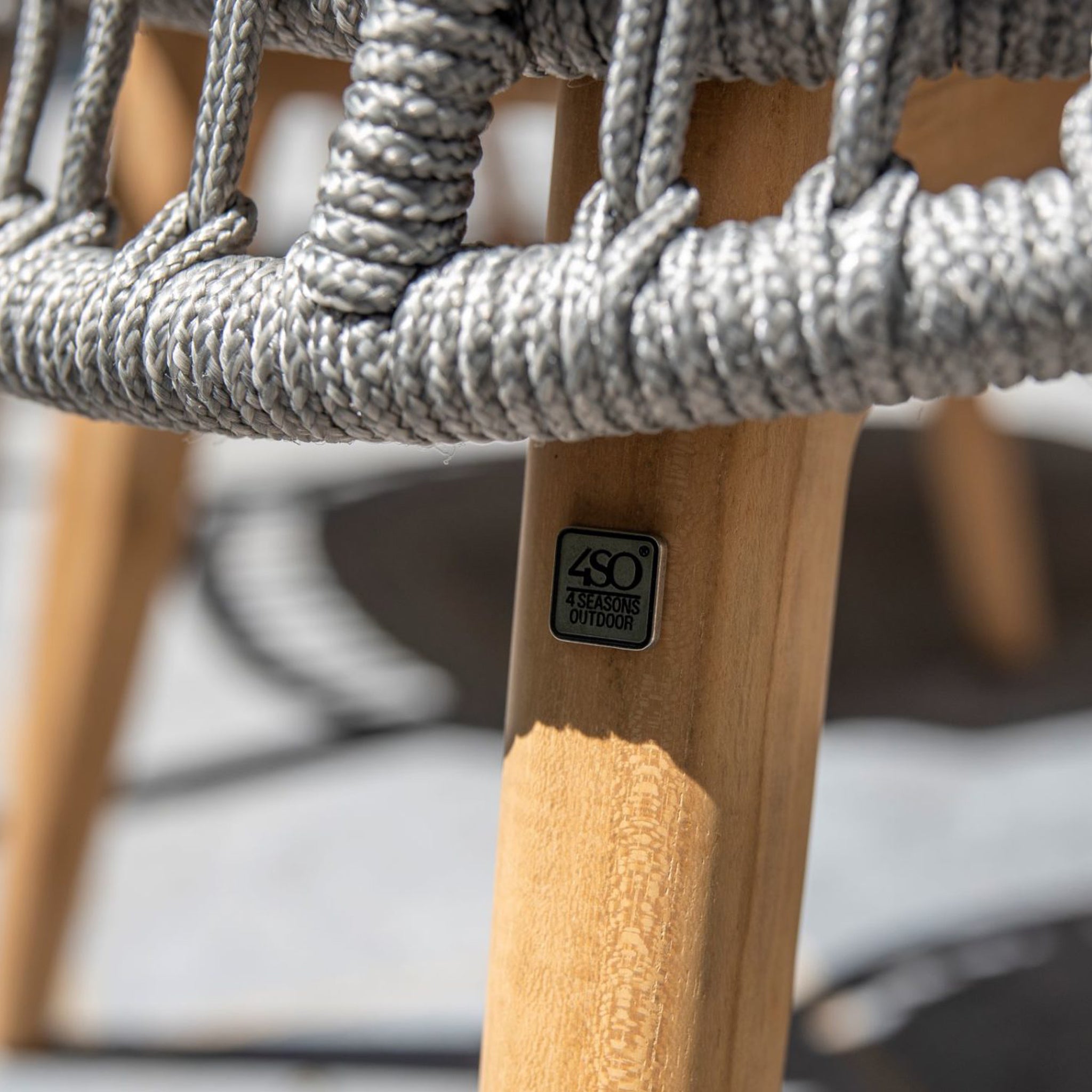 Close-up of a Sempre 6 Seat Rectangular Dining Set in light grey, featuring a handmade woven rope outdoor chair with teak wood legs and a small metal tag reading "4SO 4 Seasons Outdoor.