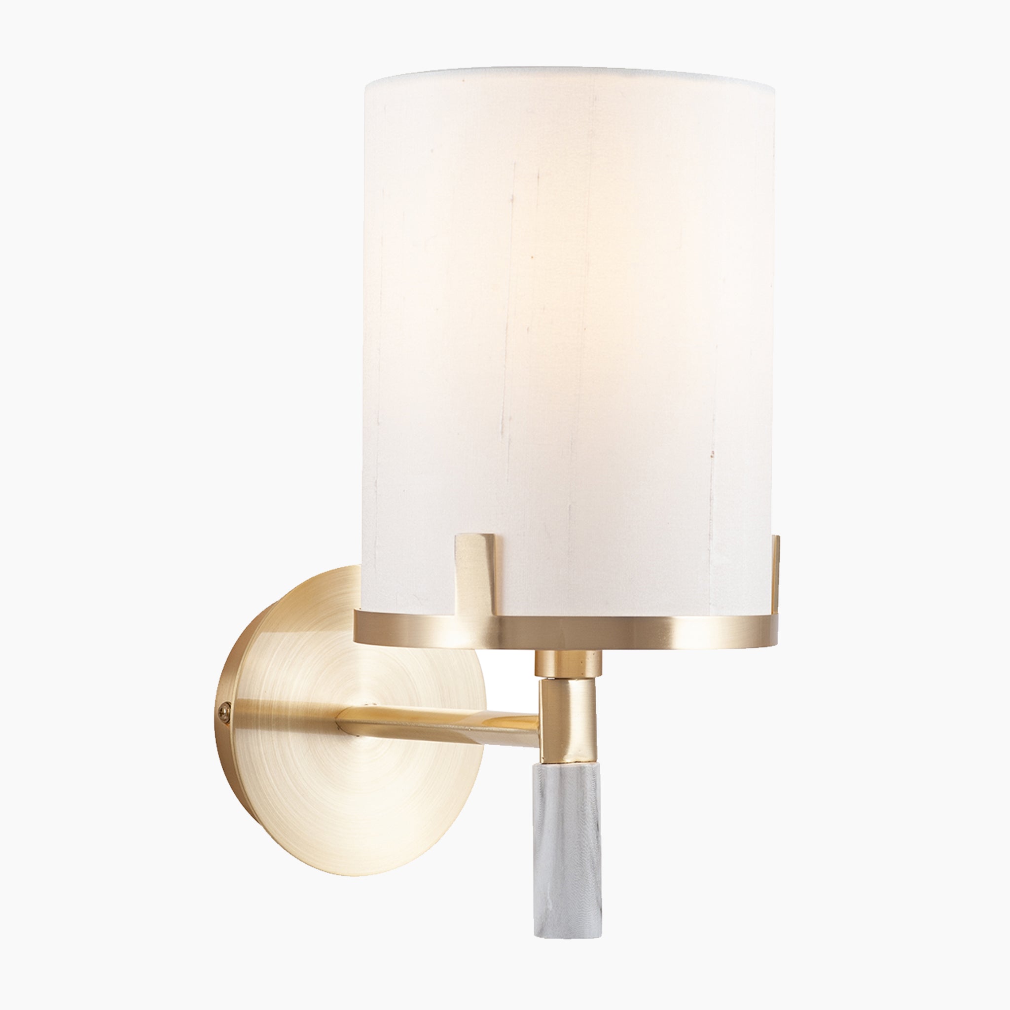 The Pacific Lifestyle Midland Champagne Gold Metal and Marble Effect Wall Light features a cylindrical white shade and gold metallic base on a white background, offering hotel-style elegance.