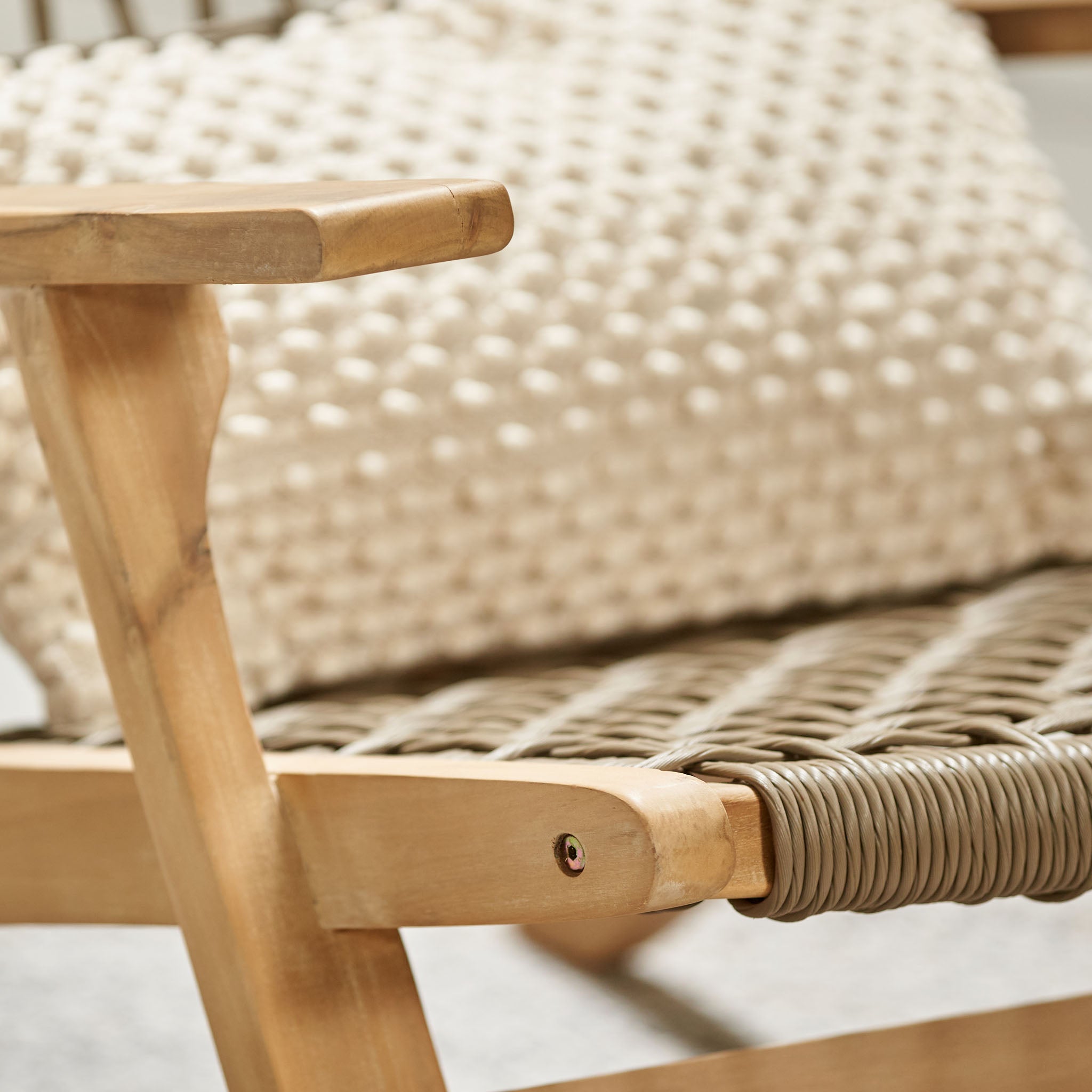 Close-up of the Pacific Lifestyle Sesto Lounge Chair made from Acacia wood, featuring a waterproof woven seat and a textured cream pillow in the background.