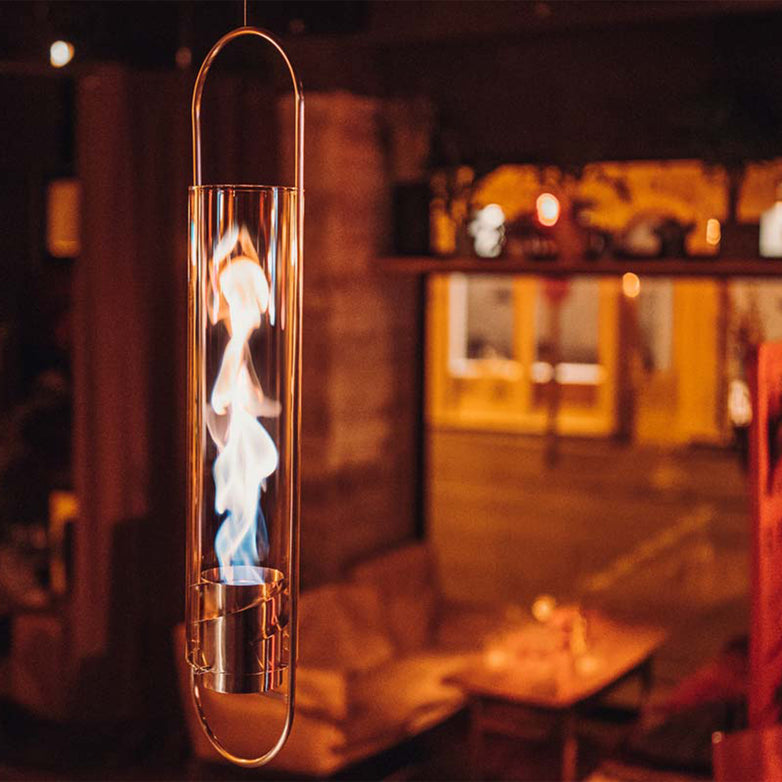 A Höfats SPIN 120 Hanging Fire in Silver features a swirling flame inside, creating a warm and cozy ambiance.